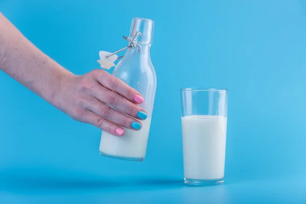 Woman Hand Pours Fresh Milk Glass Bottle Glass Blue Background — Stock Photo, Image