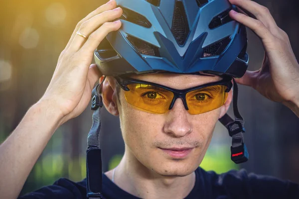 Adam bisikletçi başını yeşil doğa arka planda gri spor kask giyiyor. Dağ sırasında zorunlu koruma kavramı Bisiklet