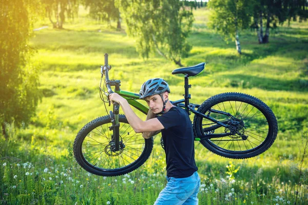 Bisikletçi adam kask içinde dağ bisikleti yeşil arka plan doğa artış taşır. Etkin ve sağlıklı yaşam kavramı