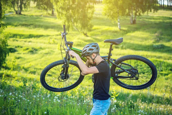 Bisikletçi adam kask içinde dağ bisikleti yeşil arka plan doğa artış taşır. Etkin ve sağlıklı yaşam kavramı