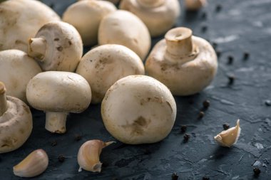 Taze beyaz Şampiyonlar, baharat ve malzemeleri karanlık mutfak masasının üzerinde. Mantar yemekleri pişirme kavramı