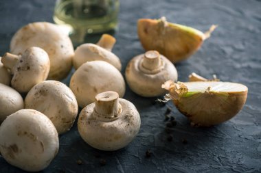 Taze beyaz Şampiyonlar, baharat ve malzemeleri karanlık mutfak masasının üzerinde. Mantar yemekleri pişirme kavramı