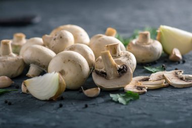 Taze beyaz Şampiyonlar, yeşil dereotu ve malzemelerin karanlık mutfak masasının üzerine. Mantar yemekleri pişirme kavramı