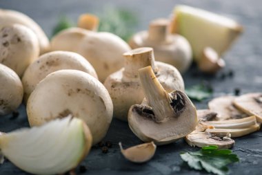 Taze beyaz Şampiyonlar, yeşil dereotu ve malzemelerin karanlık mutfak masasının üzerine. Mantar yemekleri pişirme kavramı. Yakın çekim