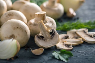 Taze beyaz Şampiyonlar, yeşil dereotu ve malzemelerin karanlık mutfak masasının üzerine. Mantar yemekleri pişirme kavramı. Yakın çekim