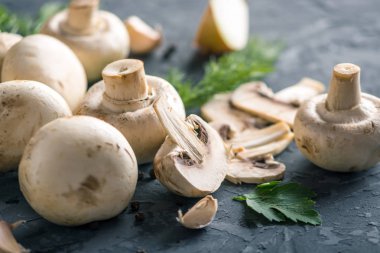 Taze beyaz Şampiyonlar, yeşil dereotu ve malzemelerin karanlık mutfak masasının üzerine. Mantar yemekleri pişirme kavramı. Yakın çekim