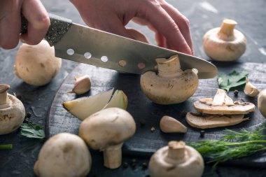 Kadınların elleri kesme petrol karanlık mutfak masasının üzerinde bir bıçakla vardır. Mantar yemekleri pişirme kavramı. Yakın çekim