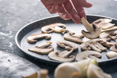 Karanlık mutfak masasının üzerinde Pan dilimlenmiş Şampiyonlar dışarı atarken el. Mantar yemekleri pişirme kavramı. Yakın çekim