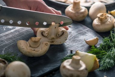 Kadınların elleri kesme petrol karanlık mutfak masasının üzerinde bir bıçakla vardır. Mantar yemekleri pişirme kavramı. Yakın çekim