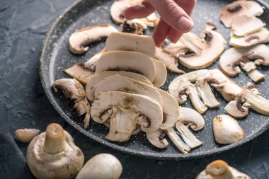 Karanlık mutfak masasının üzerinde Pan dilimlenmiş Şampiyonlar dışarı atarken el. Mantar yemekleri pişirme kavramı. Yakın çekim