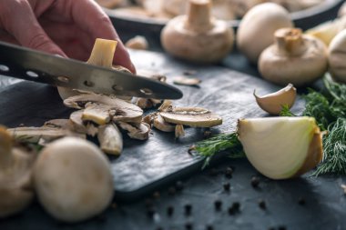 Kadınların elleri kesme petrol karanlık mutfak masasının üzerinde bir bıçakla vardır. Mantar yemekleri pişirme kavramı. Yakın çekim