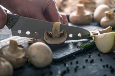 Kadınların elleri kesme petrol karanlık mutfak masasının üzerinde bir bıçakla vardır. Mantar yemekleri pişirme kavramı. Yakın çekim