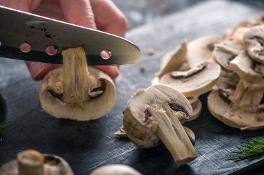 Kadınların elleri kesme petrol karanlık mutfak masasının üzerinde bir bıçakla vardır. Mantar yemekleri pişirme kavramı. Yakın çekim