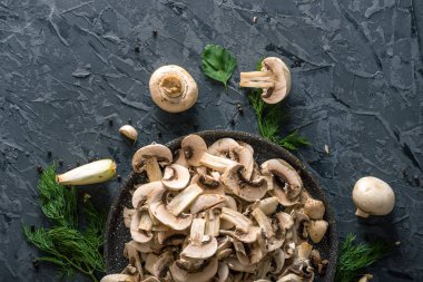 Bir tavada karanlık mutfak masasının üzerinde beyaz taze dilimlenmiş petrol. Mantar yemekleri pişirme kavramı. Yakın çekim