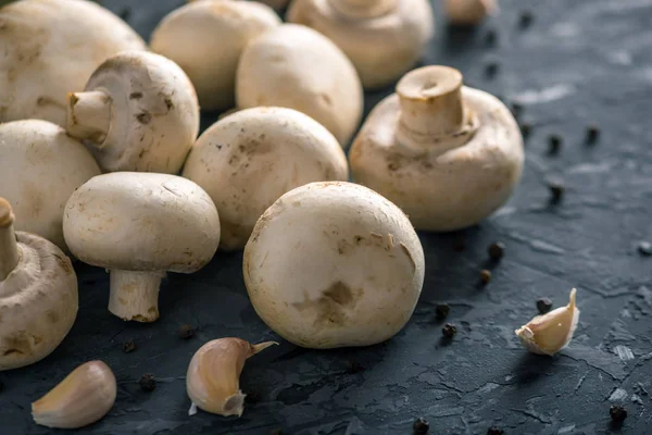 Taze beyaz Şampiyonlar, baharat ve malzemeleri karanlık mutfak masasının üzerinde. Mantar yemekleri pişirme kavramı