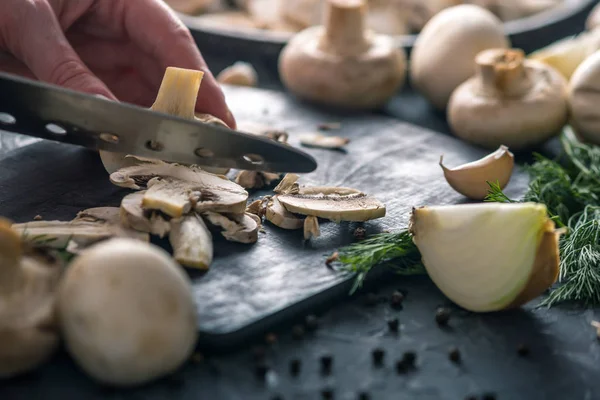 Kadınların elleri kesme petrol karanlık mutfak masasının üzerinde bir bıçakla vardır. Mantar yemekleri pişirme kavramı. Yakın çekim