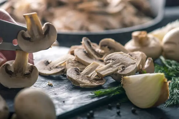 Kadınların elleri kesme petrol karanlık mutfak masasının üzerinde bir bıçakla vardır. Mantar yemekleri pişirme kavramı. Yakın çekim