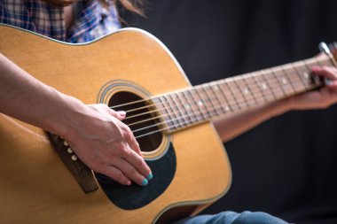 Stüdyoda karanlık bir arka plan üzerinde bir akustik gitar çalmak kız Genç. Konser genç müzisyenler