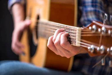 Stüdyoda karanlık bir arka plan üzerinde bir akustik gitar çalmak kız. Konser genç müzisyenler. Yakın çekim.