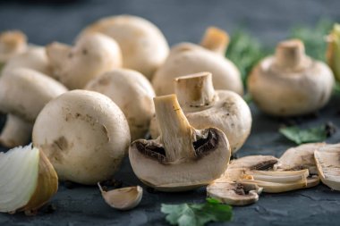 Taze beyaz Şampiyonlar, yeşil dereotu ve malzemelerin karanlık mutfak masasının üzerine. Mantar yemekleri pişirme kavramı. Yakın çekim