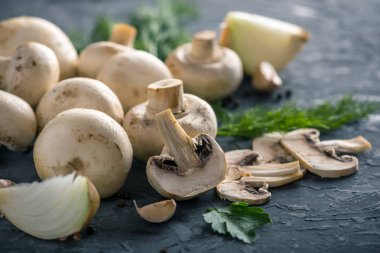 Taze beyaz Şampiyonlar, yeşil dereotu ve malzemelerin karanlık mutfak masasının üzerine. Mantar yemekleri pişirme kavramı. Yakın çekim