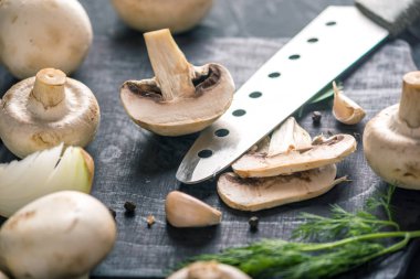 Taze beyaz Petrol bir bıçak ve karanlık mutfak masasında malzemeler ile ikiye böldüm. Mantar yemekleri pişirme kavramı. Yakın çekim
