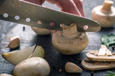 Kadınların elleri kesme petrol karanlık mutfak masasının üzerinde bir bıçakla vardır. Mantar yemekleri pişirme kavramı. Yakın çekim