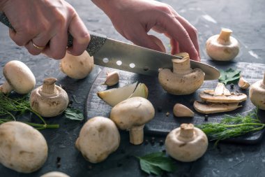 Kadınların elleri kesme petrol karanlık mutfak masasının üzerinde bir bıçakla vardır. Mantar yemekleri pişirme kavramı. Yakın çekim