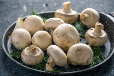 Pan ve malzemelerin karanlık mutfak masasının üzerine taze beyaz Şampiyonlar. Mantar yemekleri pişirme kavramı. Yakın çekim