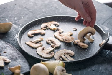 Karanlık mutfak masasının üzerinde Pan dilimlenmiş Şampiyonlar dışarı atarken el. Mantar yemekleri pişirme kavramı. Yakın çekim