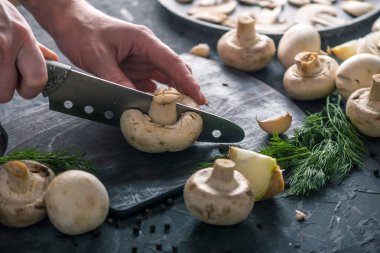 Kadınların elleri kesme petrol karanlık mutfak masasının üzerinde bir bıçakla vardır. Mantar yemekleri pişirme kavramı. Yakın çekim
