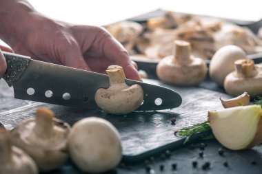 Kadınların elleri kesme petrol karanlık mutfak masasının üzerinde bir bıçakla vardır. Mantar yemekleri pişirme kavramı. Yakın çekim