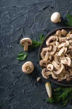 Bir tavada karanlık mutfak masasının üzerinde beyaz taze dilimlenmiş petrol. Mantar yemekleri pişirme kavramı. Yakın çekim