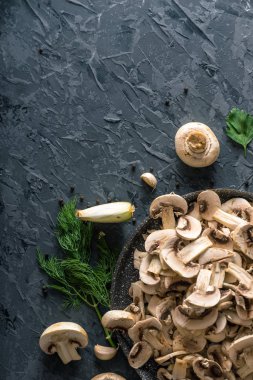 Bir tavada karanlık mutfak masasının üzerinde beyaz taze dilimlenmiş petrol. Mantar yemekleri pişirme kavramı. Yakın çekim