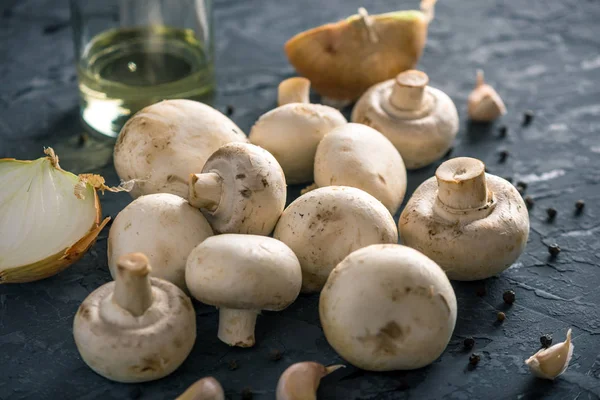 Taze beyaz Şampiyonlar, baharat ve malzemeleri karanlık mutfak masasının üzerinde. Mantar yemekleri pişirme kavramı