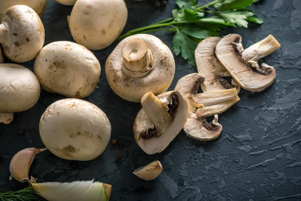 Fresh white Champions, green dill and ingredients on the dark kitchen table. The concept of cooking mushroom dishes