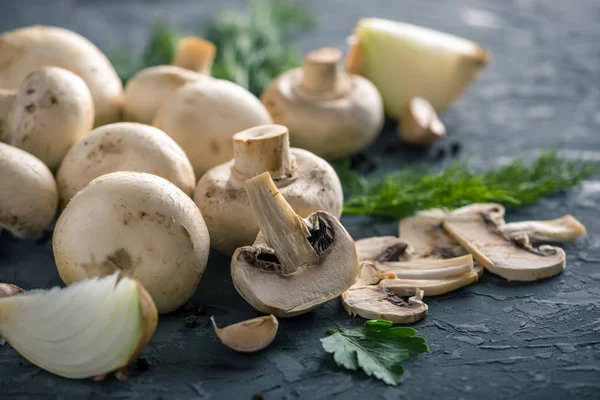 Taze beyaz Şampiyonlar, yeşil dereotu ve malzemelerin karanlık mutfak masasının üzerine. Mantar yemekleri pişirme kavramı. Yakın çekim