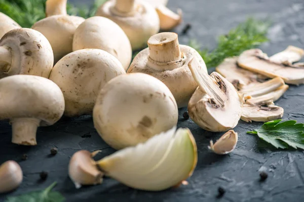 Fresh white Champions, green dill and ingredients on the dark kitchen table. The concept of cooking mushroom dishes. Close up