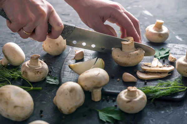 Kadınların elleri kesme petrol karanlık mutfak masasının üzerinde bir bıçakla vardır. Mantar yemekleri pişirme kavramı. Yakın çekim
