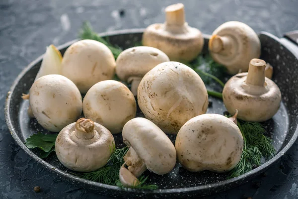 Pan ve malzemelerin karanlık mutfak masasının üzerine taze beyaz Şampiyonlar. Mantar yemekleri pişirme kavramı. Yakın çekim