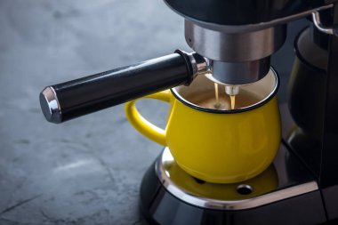 Espresso hazırlanması. Siyah kahve makinesinden sarı fincan içine dökme. Profesyonel evde bira kahve