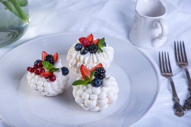 Hassas beyaz meringues plaka üzerinde taze çilek ile. Tatlı Pavlova. Beyaz arka plan. Şenlikli bir düğün pastası.