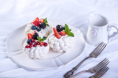 Hassas beyaz meringues plaka üzerinde taze çilek ile. Tatlı Pavlova. Beyaz arka plan. Şenlikli bir düğün pastası.