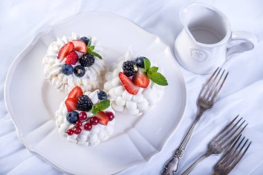 Hassas beyaz meringues plaka üzerinde taze çilek ile. Tatlı Pavlova. Beyaz arka plan. Şenlikli bir düğün pastası.