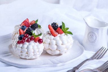 Hassas beyaz meringues plaka üzerinde taze çilek ile. Tatlı Pavlova. Beyaz arka plan. Şenlikli bir düğün pastası.