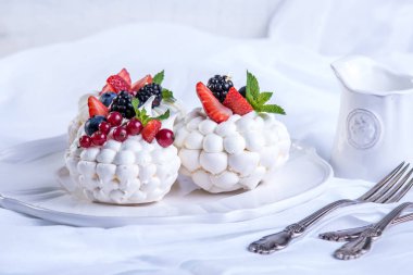 Hassas beyaz meringues plaka üzerinde taze çilek ile. Tatlı Pavlova. Beyaz arka plan. Şenlikli bir düğün pastası.