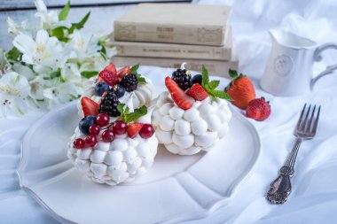 Hassas beyaz meringues plaka üzerinde taze çilek ile. Tatlı Pavlova yakın çekim. Beyaz arka plan. Şenlikli bir düğün pastası.