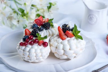 Hassas beyaz meringues plaka üzerinde taze çilek ile. Tatlı Pavlova. Beyaz arka plan. Şenlikli bir düğün pastası.