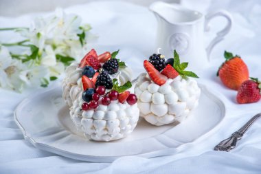 Hassas beyaz meringues plaka üzerinde taze çilek ile. Tatlı Pavlova. Beyaz arka plan. Şenlikli bir düğün pastası.