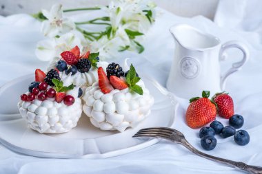 Hassas beyaz meringues plaka üzerinde taze çilek ile. Tatlı Pavlova. Beyaz arka plan. Şenlikli bir düğün pastası.